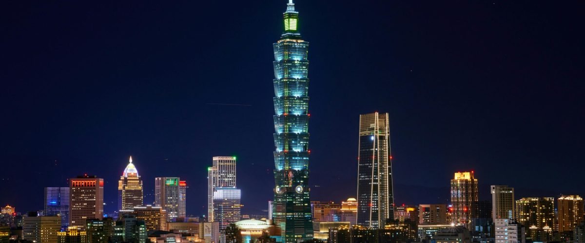 Illuminated Taipei 101 and city skyline at night showcasing modern urban architecture.